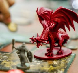 A red plastic dragon mini menaces a gray plastic warrior mini.